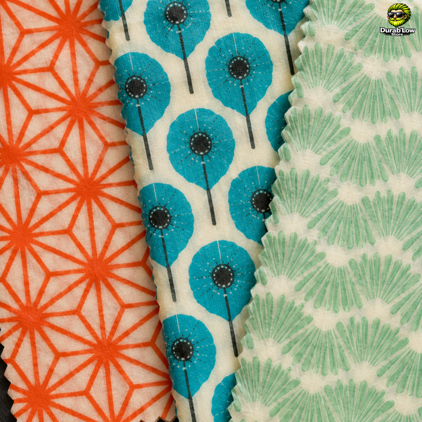 Gros plan sur les 3 motifs de beewrap L'embeillage. Le premier est un motif de traits en étoile orange, le second des fleurs bleus et le dernier des traits verts qui font penser à des feuilles.
