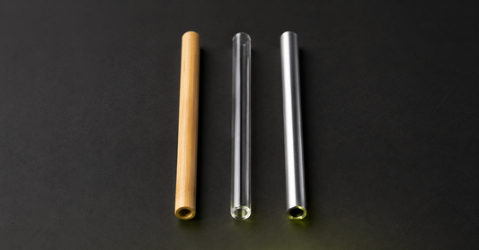 Trois pailles alignées, une paille bambou, une paille verre et une paille inox.