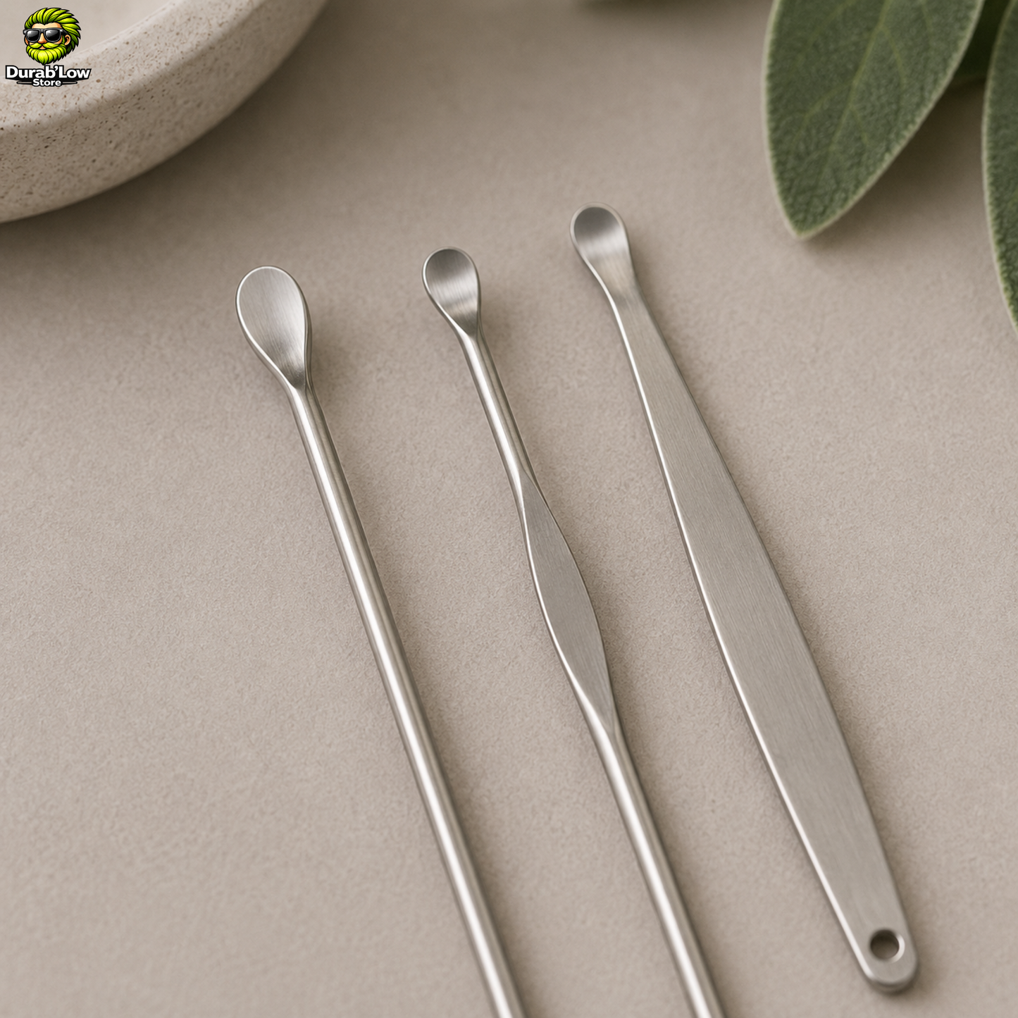 Trois oriculis en inox, embout "cuillère" disposés sur un meuble de salle de bain.