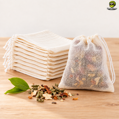 Lot de 10 sachets de thé réutilisables en coton écru, dont un rempli de thé en vrac, posé sur un plan de travail en bois clair.