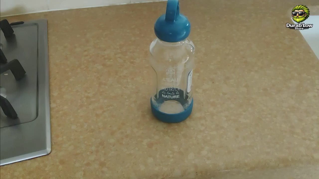 Présentation d’une gourde de 500 ml en verre borosilicate avec bouchon d’origine végétale, anneau de transport et base recyclée amovible. La vidéo montre le démontage de la gourde et précise qu’elle est fabriquée et assemblée en France.